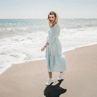 Mujer en la playa con vestido, feliz