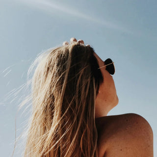 Mujer de pie bajo el sol, relajada.