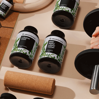 Una persona sostiene una botella de suplementos dietéticos naturales en una mesa.