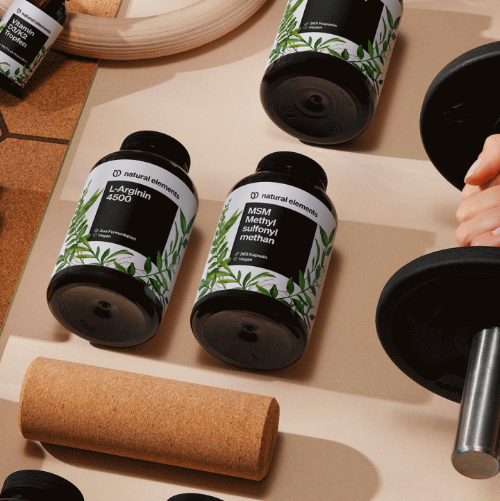 Una persona sostiene una botella de suplementos dietéticos naturales en una mesa.