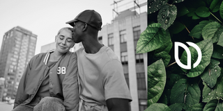 Una pareja joven sentada junta en una azotea de la ciudad; el hombre besa la sien de la mujer. A la derecha, se ven hojas verdes con gotas de agua y un logo blanco abstracto.