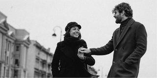 Una foto en blanco y negro de un hombre y una mujer tomados de la mano, capturando su conexión entre elementos naturales.