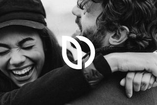Una foto en blanco y negro de un hombre y una mujer abrazándose, rodeados de elementos naturales.