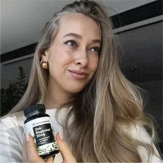 Una mujer sostiene una botella de vitamina C derivada de elementos naturales.